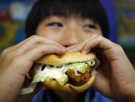 A boy poses with a chicken burger at a fast food outlet in Taipei January 29, 2010. REUTERS/Nicky Loh/Files