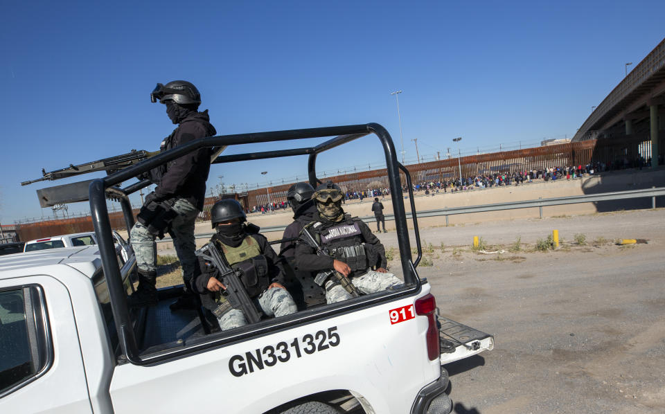 Mexican National Guard patrols the southern bank of the Rio Grande as hundreds of migrants wait in line to enter into El Paso, Texas from Ciudad Juarez, Mexico, Wednesday, Dec. 21, 2022. Thousands of migrants gathered along the Mexican side of the southern border Wednesday, camping outside or packing into shelters as they waited for the U.S. Supreme Court to decide whether and when to lift pandemic-era restrictions that have prevented many from seeking asylum. (AP Photo/Andres Leighton)