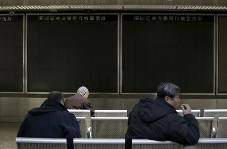 People sit in front of an electronic boarding that was turned off after trading was suspended, at a brokerage house, in Beijing, China, January 7, 2016. REUTERS/Jason Lee