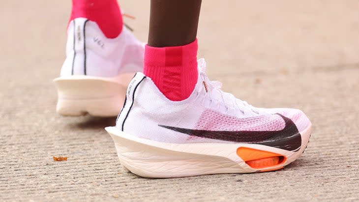 a closeup photo of a white nike shoe with red socks