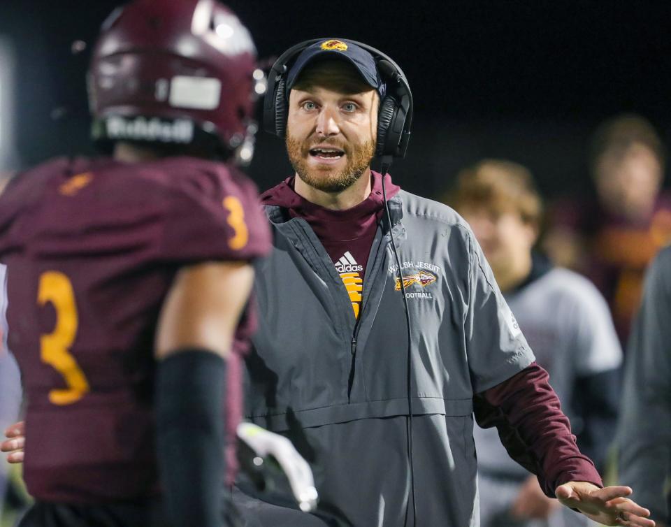 Walsh Jesuit head coach Nick Alexander talks with Tre Bell on the sidelines during a game against St. Vincent-St. Mary on Oct. 21, 2022.