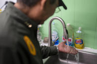 Dan Martinez, emergency manager for the Confederated Tribes of Warm Springs, examines the tap water available in his office on Monday, Dec. 6, 2021, in Warm Springs, Ore. The massive infrastructure bill signed earlier this year promises to bring change to some Native American tribes that lack clean water or indoor plumbing through the largest single infusion of money into Indian Country. (AP Photo/Nathan Howard)