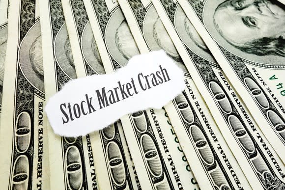 the words stock market crash printed on a torn piece of paper sitting on a bed of hundred dollar bills