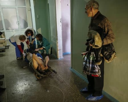 Medics help an injured Ukrainian serviceman as a local resident looks on at a hospital in Artemivsk February 8, 2015. REUTERS/Gleb Garanich