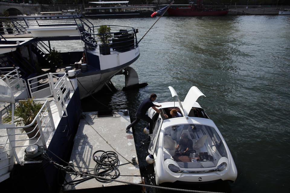 In this photo taken Tuesday Sept. 17, 2019 a man steps into an hydrofoil boat SeaBubble in Paris. Paris is testing out a new form of travel - an eco-friendly bubble-shaped taxi that zips along the water, capable of whisking passengers up and down the Seine River. (AP Photo/Francois Mori)