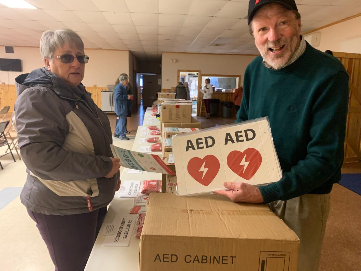 Jim White (right) helps hand out automated external defibrillators on Friday, Feb. 24 at the Boyne City Eagles Lodge after purchasing 13 for local churches and the local American Legion post.