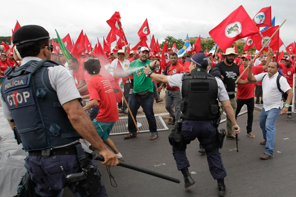 Brazilian riot police clash with demonstrators during a march of The Landless Workers Movement, in front of the Planalto presidential palace, in Brasilia, Brazil, Wednesday, Feb. 12, 2014. The Landless Workers Movement, one of the globe’s biggest agrarian reform movements called the protest to demand that the government hand over more unused land to impoverished farmers who have none of their own. (AP Photo/Eraldo Peres)