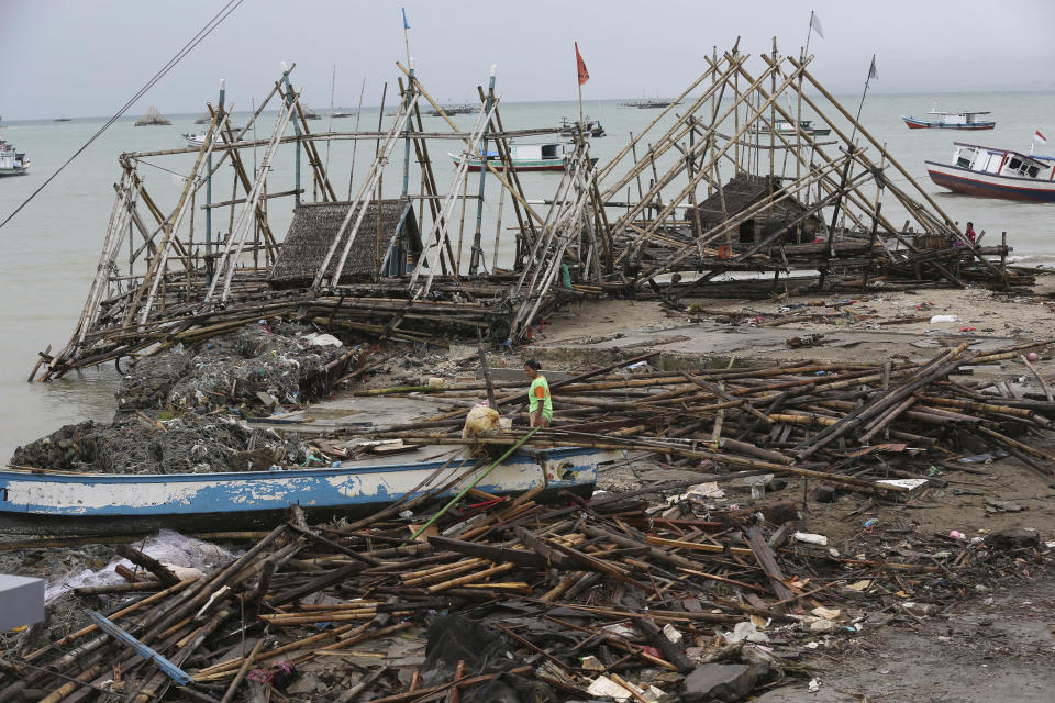 A woman walks amid debris at a tsunami-ravaged village in Sumur, Indonesia, Tuesday, Dec. 25, 2018. The Christmas holiday was somber with prayers for tsunami victims in the Indonesian region hit by waves that struck without warning Saturday night.(AP Photo/Tatan Syuflana)