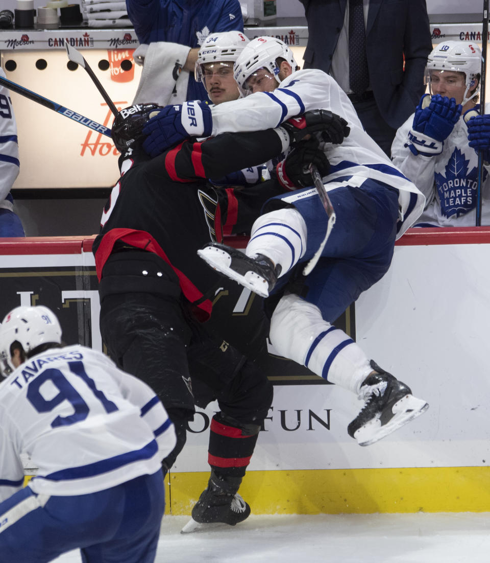 Ottawa Senators left wing Austin Watson collides with Toronto Maple Leafs defenseman Jake Muzzin along the boards during the third period of an NHL hockey game in Ottawa, Ontario, Saturday, Jan. 16, 2021. (Adrian Wyld/The Canadian Press via AP)