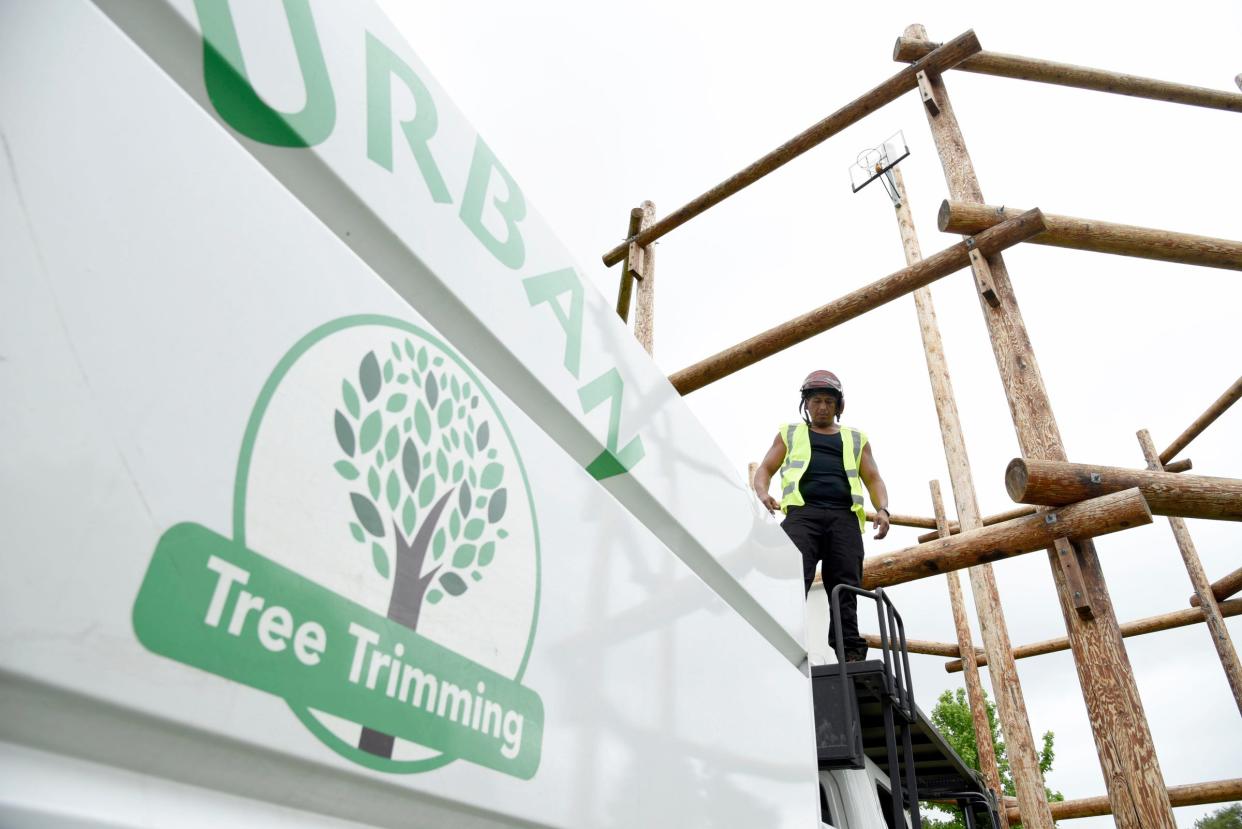 Efren Esquivel, 45, of Detroit, stands on top of the Urban Tree Trimming truck, getting ready to move trainees up 80 feet to shoot the ball into the basket as part of the training exercise at the Tree Trim Academy in Detroit on Tuesday, June 7, 2022.