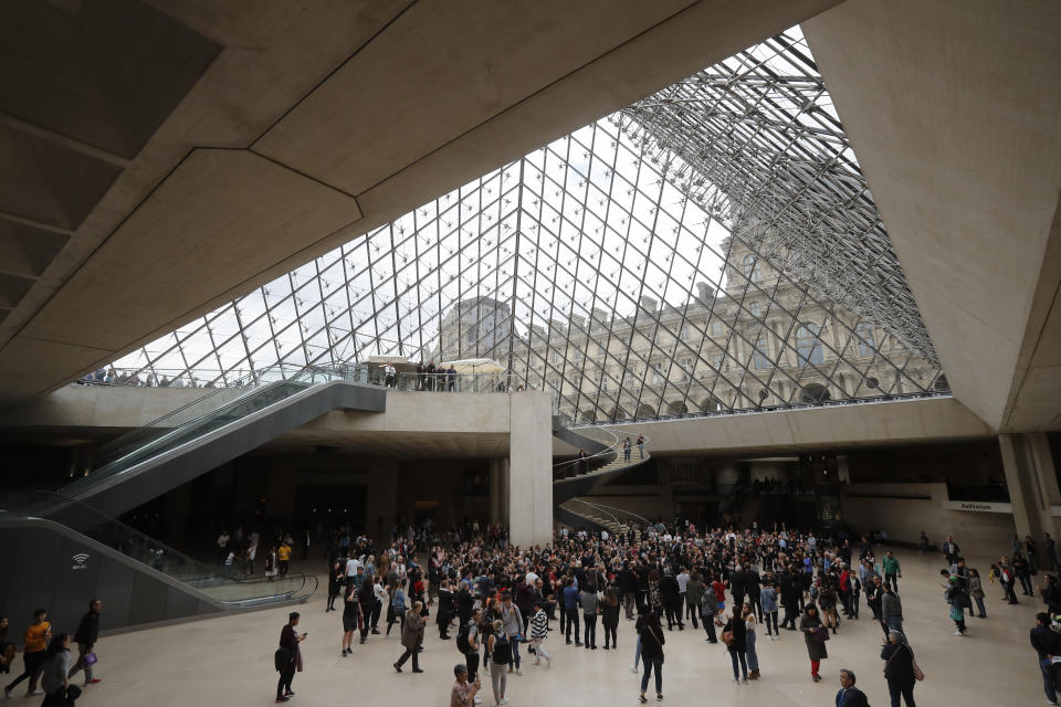 Le Louvre museum employees and tourist gather under the giant glass pyramid by late architect I.M. Pei, Friday, May 17, 2019 in Paris. Pei died earlier this week at the age of 102. (AP Photo/Michel Euler)