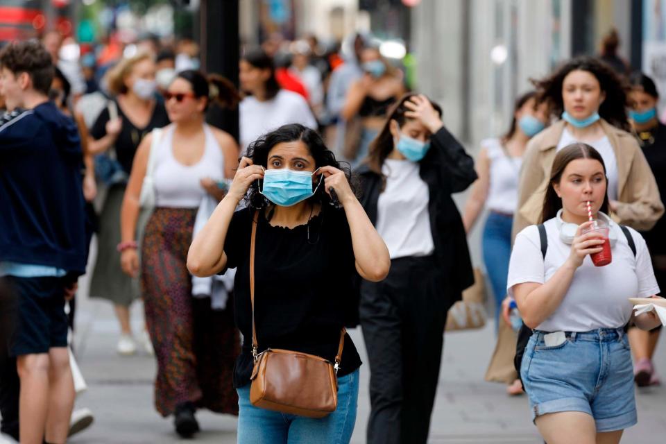 A shopper adjusts her face mask on Oxford Stree: AFP via Getty Images