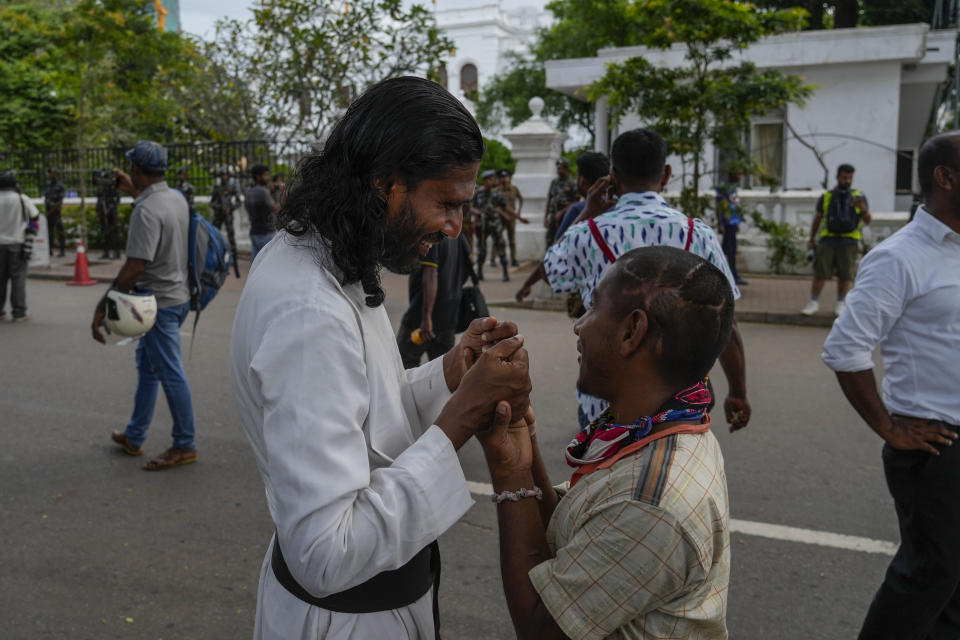 Two protesters greet each other as they leave prime minister Ranil Wickremesinghe's office building in Colombo, Sri Lanka, Thursday, July 14, 2022. Sri Lankan protesters began to retreat from government buildings they seized and military troops reinforced security at the Parliament on Thursday, establishing a tenuous calm in a country in both economic meltdown and political limbo. (AP Photo/Rafiq Maqbool)