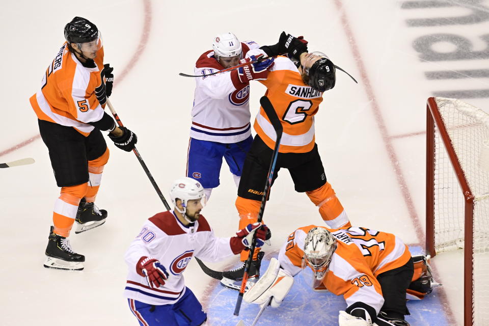 Montreal Canadiens left wing Tomas Tatar (90), foreground, starts to celebrate his goal against Philadelphia Flyers goaltender Carter Hart (79) as Canadiens right wing Brendan Gallagher (11) and Flyers defenseman Travis Sanheim (6) battle in front of the net during the first period of an NHL hockey Eastern Conference Stanley Cup first round playoff game in Toronto on Thursday, Aug. 14, 2020. (Frank Gunn/The Canadian Press via AP)