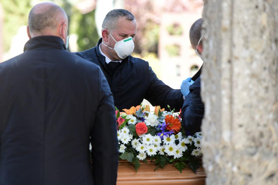 Undertakers wearing a face mask unload a coffin out of a hearse on March 16, 2020 at the Monumental cemetery of Bergamo, Lombardy, as burials of people who died of the new coronavirus are being conducted at the rythm of one every half hour. (Photo by Piero Cruciatti / AFP) (Photo by PIERO CRUCIATTI/AFP via Getty Images)