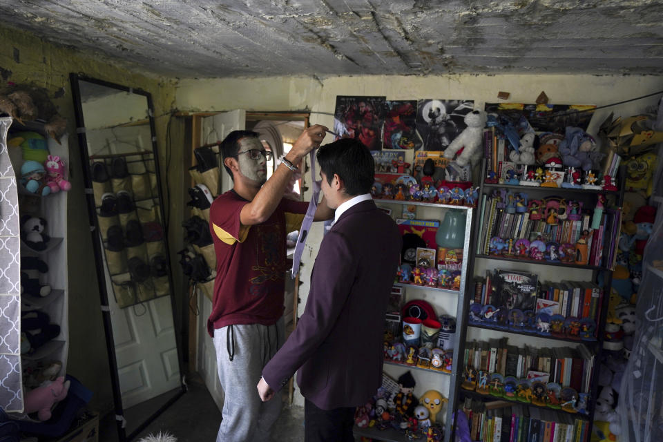 Eliha Rendon, wearing a mood facial mask, puts a necktie on his fiancé Javier Vega, before they get married in a mass wedding ceremony organized by city authorities as part of the LGBT pride month celebrations, in Mexico City, Friday, June 24, 2022. (AP Photo/Fernando Llano)