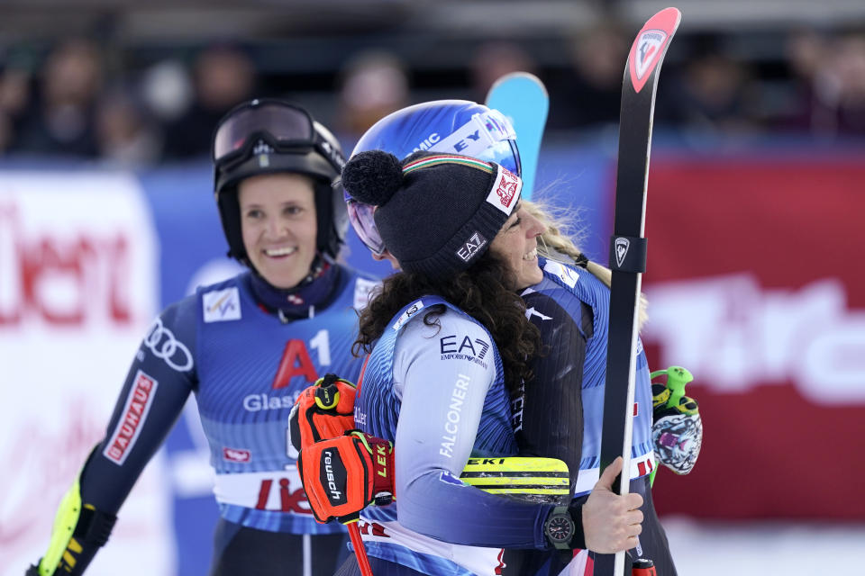 United States' Mikaela Shiffrin, right, winner of an alpine ski, women's World Cup giant slalom race, is hugged by second-placed Italy's Federica Brignone, left, as third-placed Sweden's Sara Hector, background, smiles, in Lienz, Austria, Thursday, Dec. 28, 2023. (AP Photo/Giovanni Auletta)