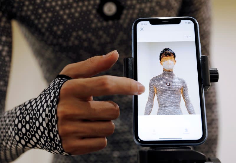 An employee of online fashion retailer Zozo Inc. demonstrates the company's Zozosuit 2, a 3D body measurement suit, in Tokyo