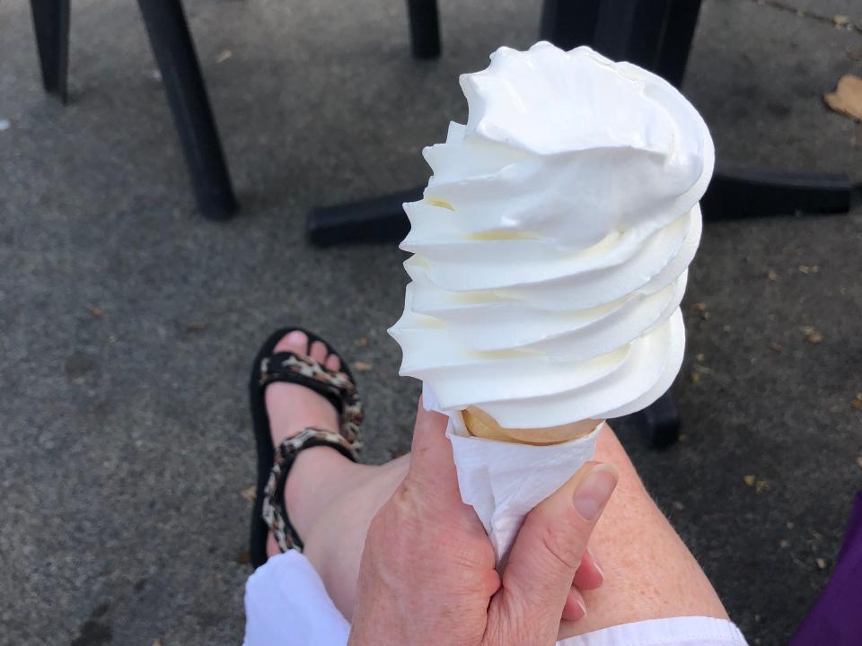 hand holding a vanilla soft serve cone at an outdoor picnic table in victoria ca