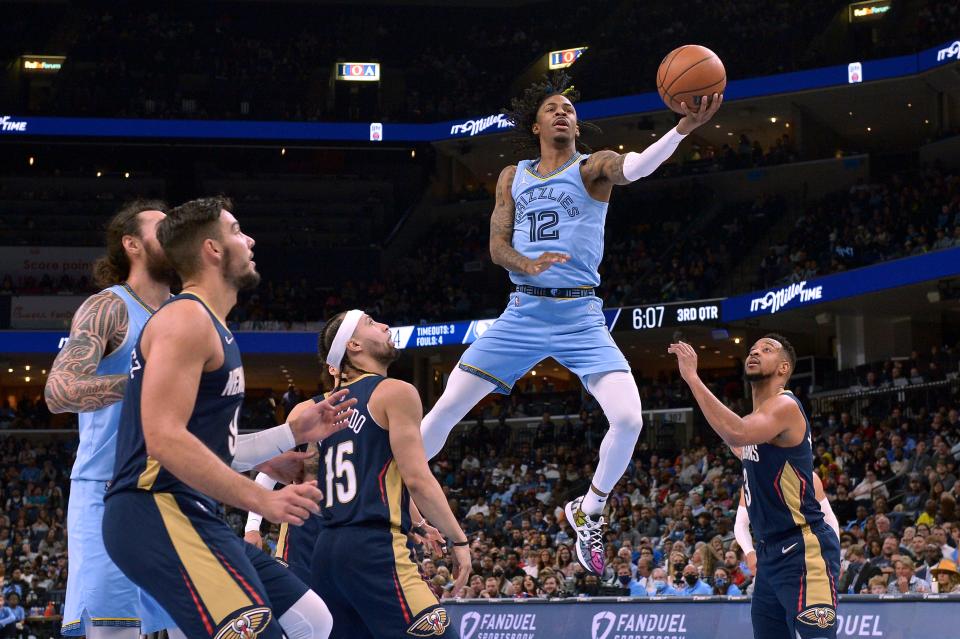 Memphis Grizzlies guard Ja Morant (12) jumps to shoot between New Orleans Pelicans guards Jose Alvarado (15) and CJ McCollum (3) during the second half of an NBA basketball game Saturday, April 9, 2022, in Memphis, Tenn. (AP Photo/Brandon Dill)