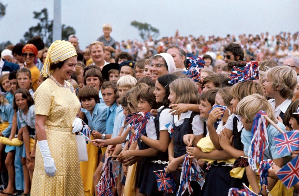 The Queen meets flag-waving school children in Brisbane during her Silver Jubilee Tour of Australia (PA) (PA Archive)