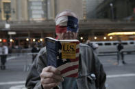 A blindfolded demonstrator holds up a copy of the United States Constitution while protesting against Donald Trump in midtown Manhattan in New York City, April 14, 2016. REUTERS/Mike Segar