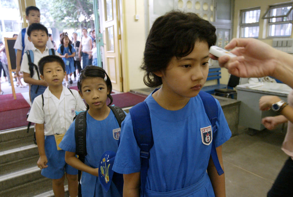 Students of SKH Yat San Primary School line up to have temperature check for the SARS precaution on the first day of the new school year. September 1, 2003 (David Wong/South China Morning Post via Getty Images)