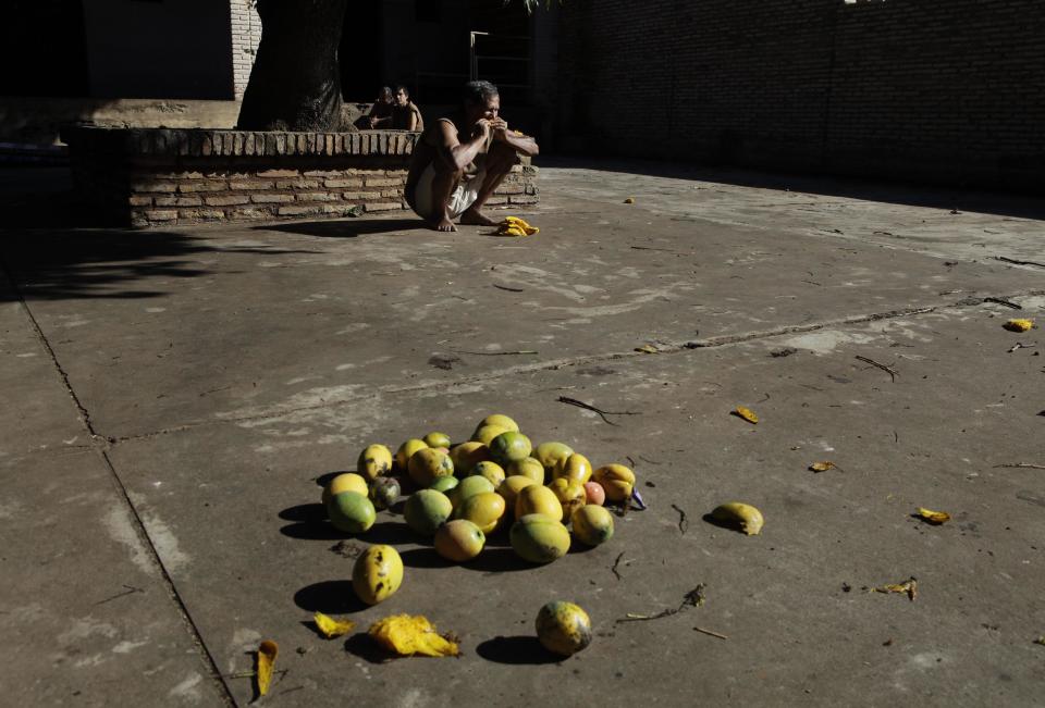 In this May 29, 2013 photo, a patient eats mangos in the courtyard of the Neuro-Psychiatric Hospital in Asuncion, Paraguay. Paraguay's only public psychiatric hospital is forced to feed hundreds of patients with donated food for lack of funding. (AP Photo/Jorge Saenz)