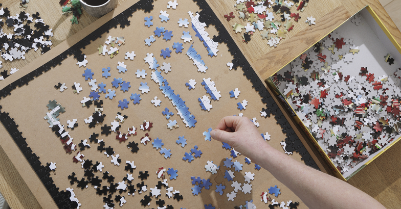 hands doing a large puzzle with a cup of coffee