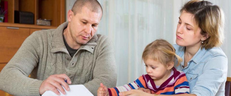 Upset couple with child sitting at the table with financial documents