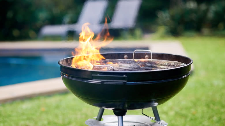 charcoal grill with flames on green lawn