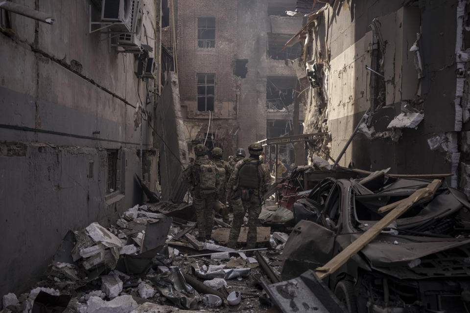 FILE - Ukrainian servicemen walk among debris of damaged buildings after a Russian attack in Kharkiv, Ukraine, Saturday, April 16, 2022. As milestones go, the first anniversary of Russia's invasion of Ukraine is both grim and vexing. It marks a full year of killing, destruction, loss and pain felt even beyond the borders of Russia and Ukraine. (AP Photo/Felipe Dana, File)