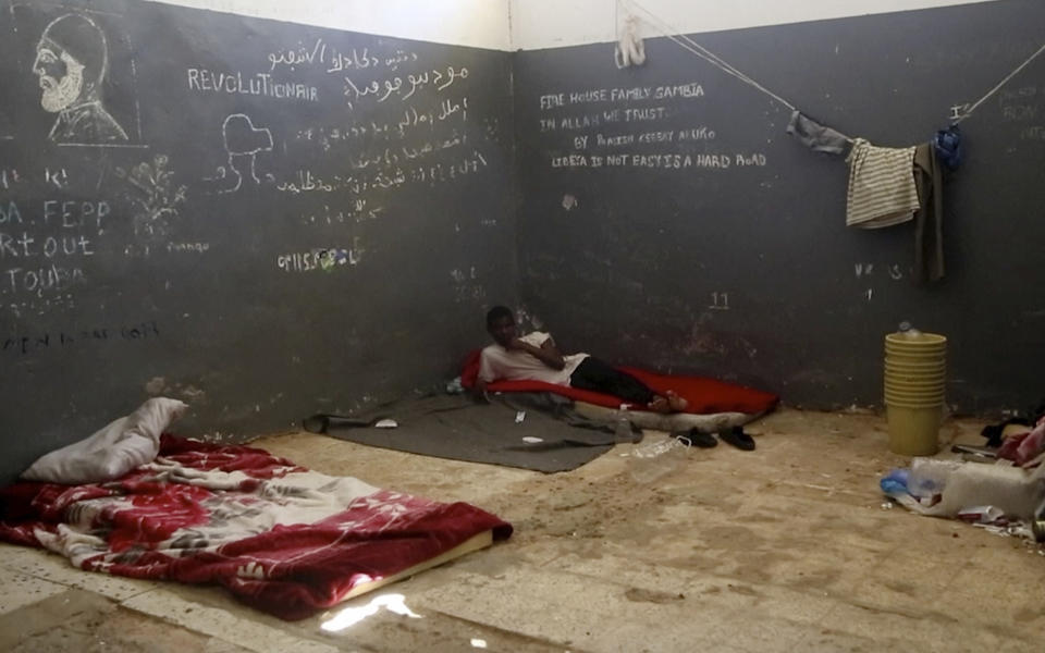 In this Wednesday, July 17, 2019 frame grab from video, a migrant rests in a detention center in the city of Sabha, which is about 650 kilometers, or 400 miles, south of the capital, Tripoli, Libya. Migrants held at a small, dilapidated detention center in the southern Libyan city of Sabha say they are being neglected by international organizations and often go hungry due to lack of food. (AP Photo)