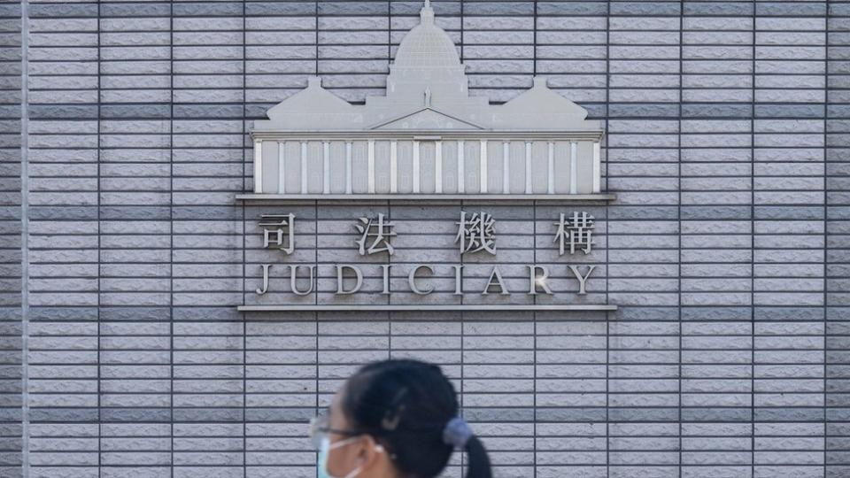 一位女孩走過香港西九龍法院大樓的香港司法機構標誌（13/7/2020）