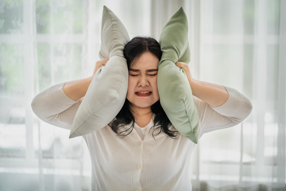 Fat woman covering her ears with a pillow, the concept does not want to hear things. affecting oneself