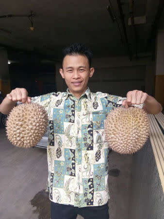 A man poses with two J-Queen durians in Jakarta, Indonesia January 25, 2019 in this picture obtained from social media. INSTAGRAM / @PLAZAASIA.OFFICIAL/via REUTERS