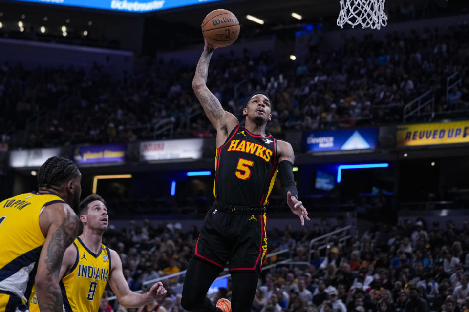 Atlanta Hawks guard Dejounte Murray (5) goes up for a dunk in front of Indiana Pacers guard T.J. McConnell (9) during the first half of an NBA basketball game in Indianapolis, Sunday, April 14, 2024. (AP Photo/Michael Conroy)