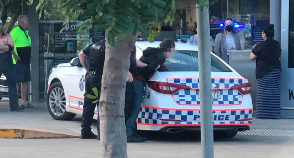 A man is held against a police car by officers in Booval. 