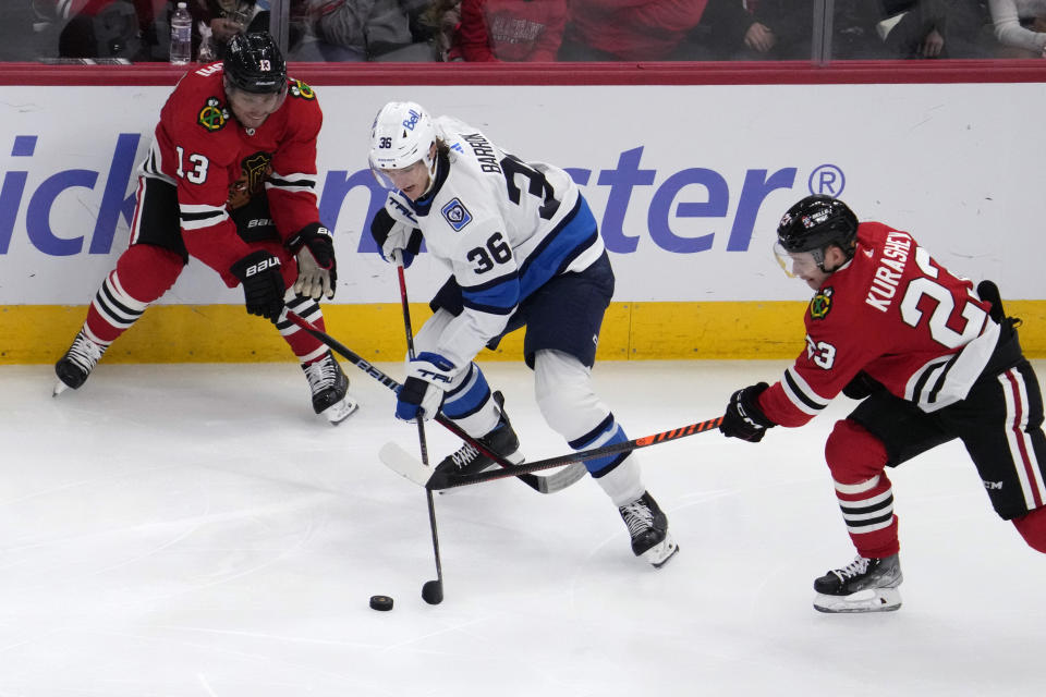 Winnipeg Jets center Morgan Barron (36) controls the puck against Chicago Blackhawks center Max Domi, left, and center Philipp Kurashev during the second period of an NHL hockey game in Chicago, Friday, Dec. 9, 2022. (AP Photo/Nam Y. Huh)