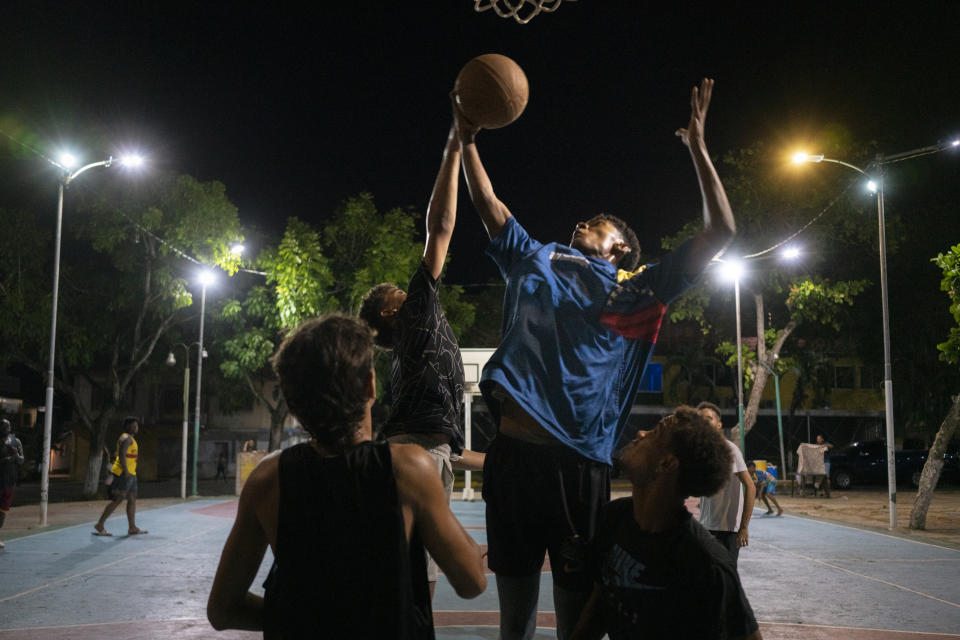 Young men play basketball as the sun sets. (Andrea Hernández Briceño for The Washington Post)