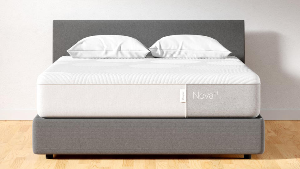Casper mattress deals, sales and discounts: the Casper Nova Hybrid mattress in white dressed with two white pillows and sat on a grey fabric bed frame