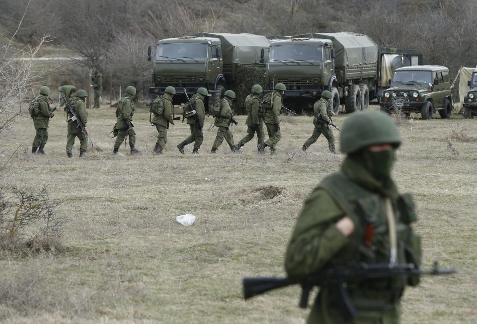 Military personnel, believed to be Russian servicemen, march outside the territory of a Ukrainian military unit in the village of Perevalnoye outside Simferopol