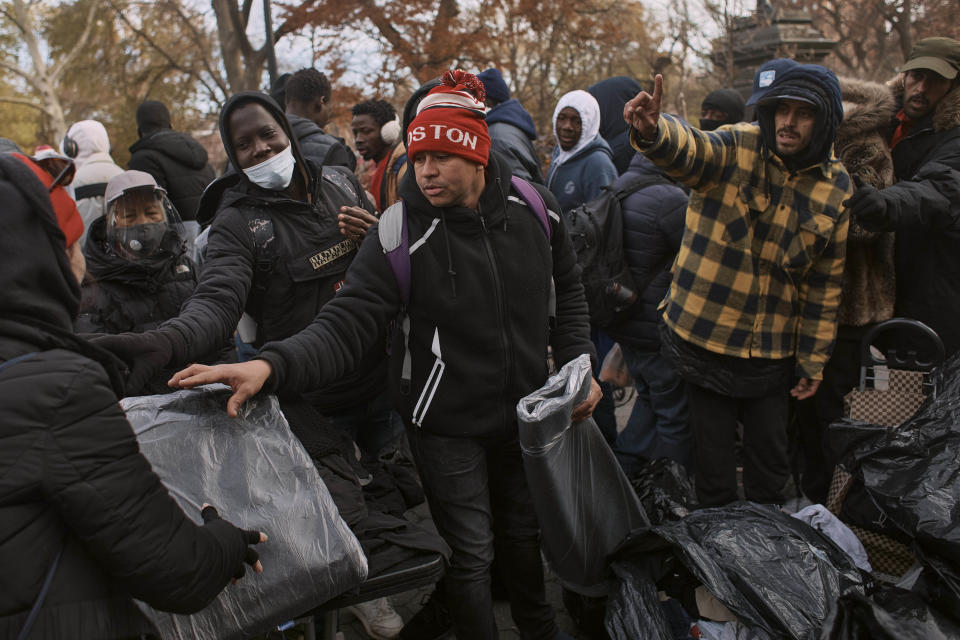 Migrants pick up blankets near a migrant assistance center at St. Brigid Elementary School on Tuesday, Dec. 5, 2023, in New York. It could be a cold, grim New Year for thousands of migrant families living in New York City’s emergency shelter system. With winter setting in, they are being told they need to clear out, with no guarantee they’ll be given a bed elsewhere. (AP Photo/Andres Kudacki)