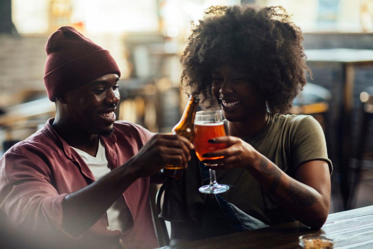 man and woman cheers while drinking beer