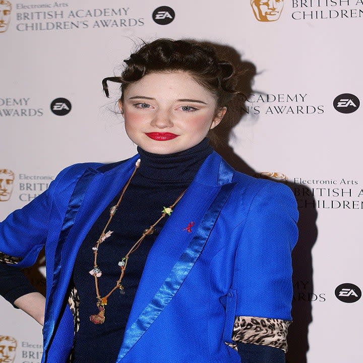 Andrea Riseborough a red carpet event wearing a turtleneck and a blazer with satin-trimmed lapels. Andrea's hair is also swept into an updo