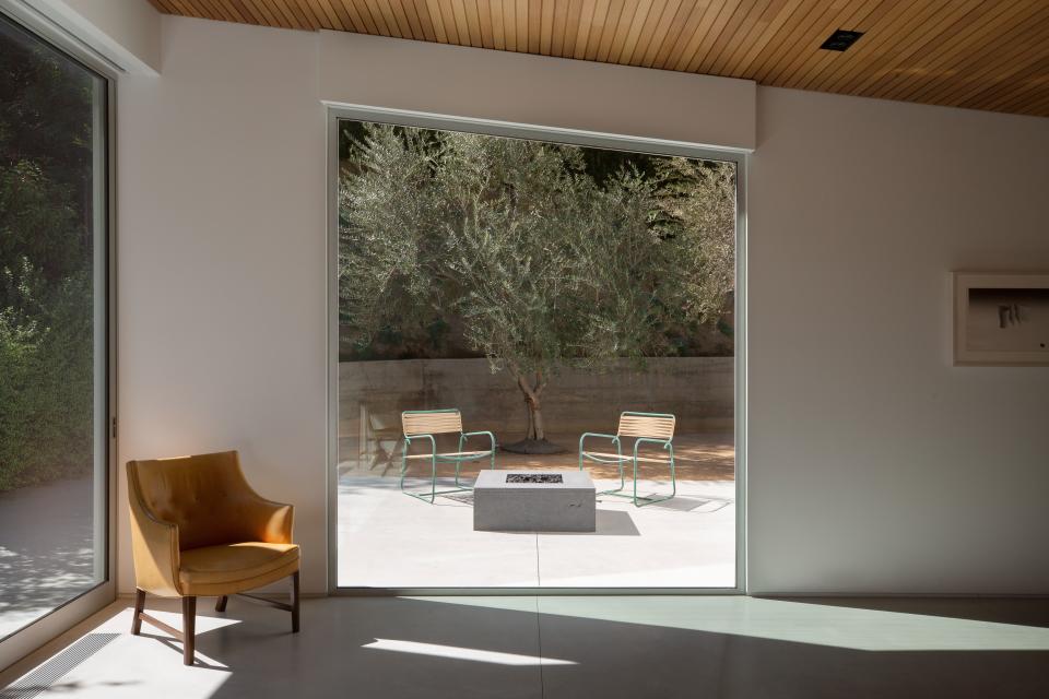 The same concrete was used both indoors and outdoors, which ties the spaces together. The fire pit is from Basaltina, the chairs are Walter Lamb, and the armchair inside is by Frits Henningsen.