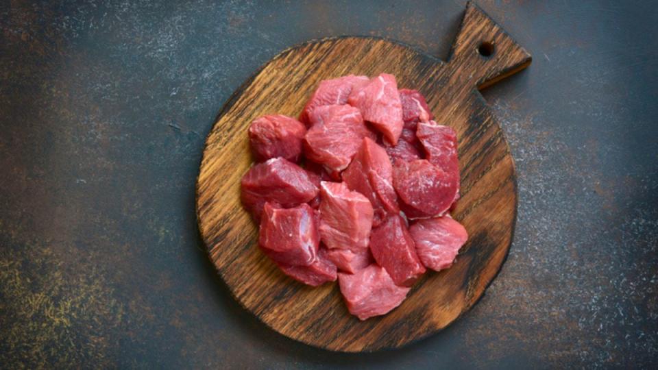 steak cut into cubes on wooden cutting board