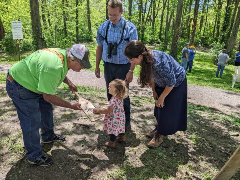Mike Quirin, founder of Richland Creek Improvement Association, shows a young fishing enthusiast a hand-painted paddle at a scavenger hunt that the organization hosted last year.