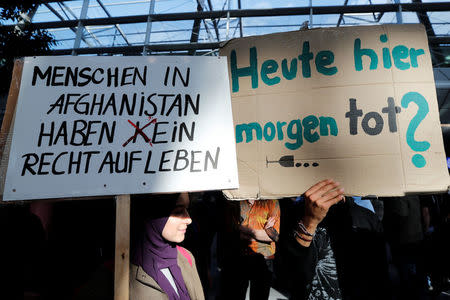 People hold signs as they protest against the German government's decision to deport migrants who were denied asylum, at Duesseldorf Airport, Germany September 12, 2017. Signs read (L-R): "People in Afghanistan do (not) have a right to live", "Here today, dead tomorrow?". REUTERS/Wolfgang Rattay