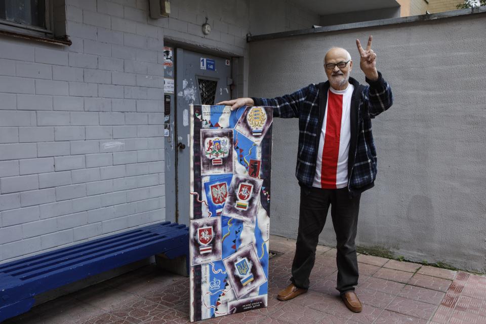 Ales Marachkin, 80, poses for a photo with a poster showing Belarus's neighboring countries at the entrance of his apartment building in Minsk, Belarus, Sunday, Sept. 13, 2020. Marachkin, a 80-year-old painter, denounces the Belarusian leader who frequently admired the Soviet Union as a "Soviet holdover." The authorities have barred Marachkin from having personal exhibitions and removed his paintings from the national art museum. (AP Photo)